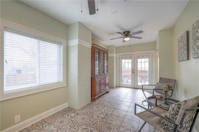 living area featuring a ceiling fan, light tile patterned floors, french doors, and baseboards