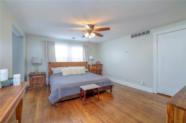 bedroom featuring baseboards, wood finished floors, visible vents, and ceiling fan