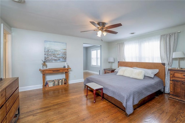 bedroom featuring visible vents, a ceiling fan, baseboards, and wood finished floors