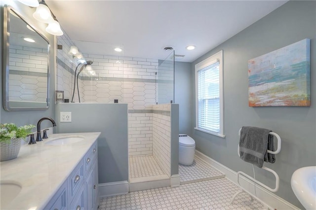 full bathroom with baseboards, double vanity, a sink, walk in shower, and toilet