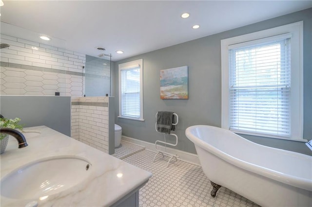 full bathroom with baseboards, double vanity, a freestanding tub, a tile shower, and a sink