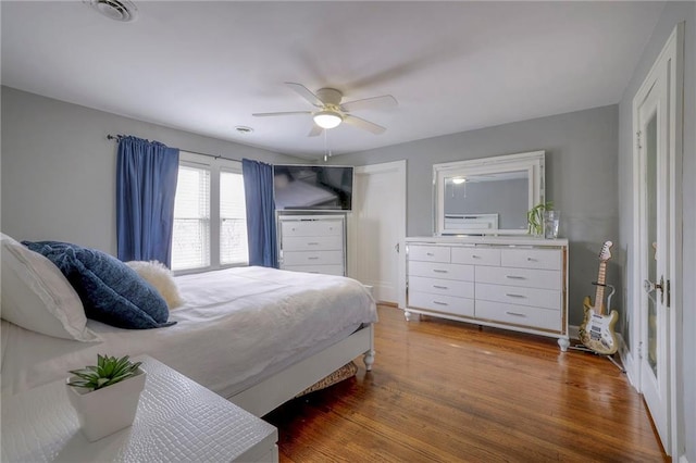 bedroom with ceiling fan, visible vents, and wood finished floors