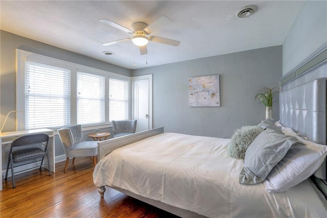 bedroom featuring visible vents, a textured ceiling, and wood finished floors