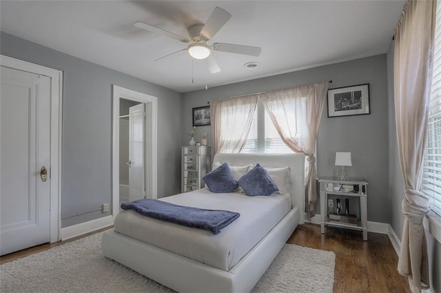 bedroom with visible vents, ceiling fan, baseboards, ensuite bathroom, and wood finished floors