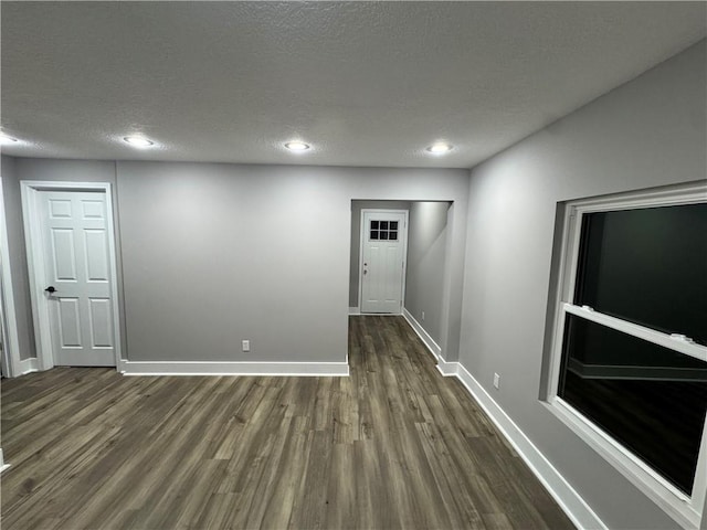 spare room featuring recessed lighting, dark wood-style flooring, a textured ceiling, and baseboards