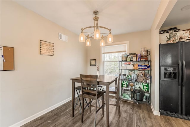 dining room featuring an inviting chandelier, visible vents, baseboards, and wood finished floors