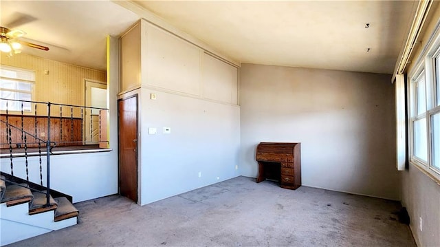 carpeted spare room with stairway and a ceiling fan