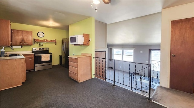 kitchen featuring brown cabinets, a sink, stainless steel appliances, light countertops, and ceiling fan