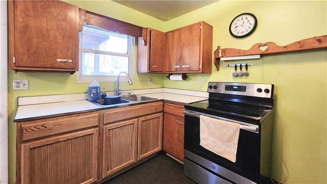 kitchen with brown cabinetry, stainless steel range with electric cooktop, light countertops, and a sink