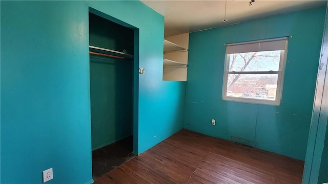 unfurnished bedroom with a closet, visible vents, and wood finished floors