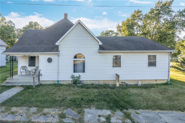 back of house featuring a shingled roof, a chimney, and a yard