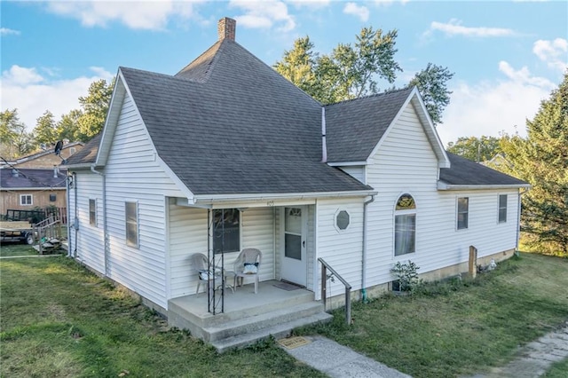 view of front of home featuring a shingled roof, a front yard, and a chimney