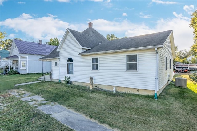 back of house with central AC, a shingled roof, a lawn, and a chimney