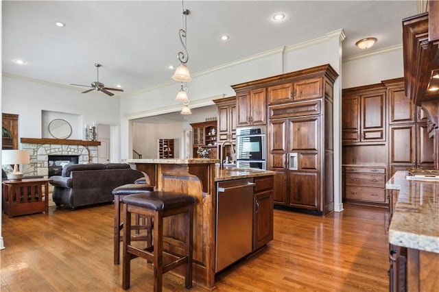 15300 Mastin St, Overland Park, KS 66221 - kitchen featuring paneled refrigerator, ceiling fan, a kitchen bar, light stone counters, and decorative light fixtures