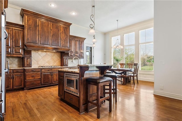 15300 Mastin St, Overland Park, KS 66221 - kitchen featuring crown molding, backsplash, a breakfast bar, appliances with stainless steel finishes, and dark wood-style floors