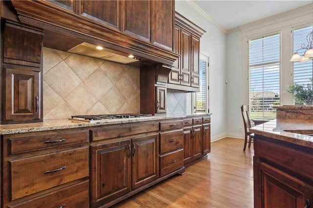 15300 Mastin St, Overland Park, KS 66221 - kitchen with custom exhaust hood, ornamental molding, stainless steel gas stovetop, wood finished floors, and light stone countertops
