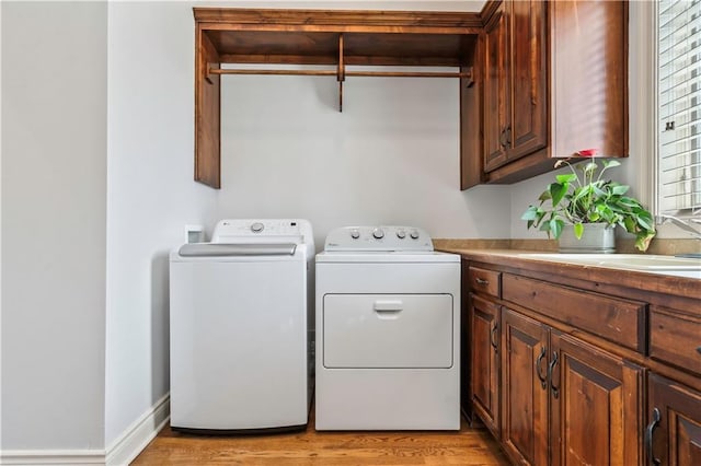 15300 Mastin St, Overland Park, KS 66221 - clothes washing area featuring independent washer and dryer, a sink, cabinet space, and light wood-style flooring