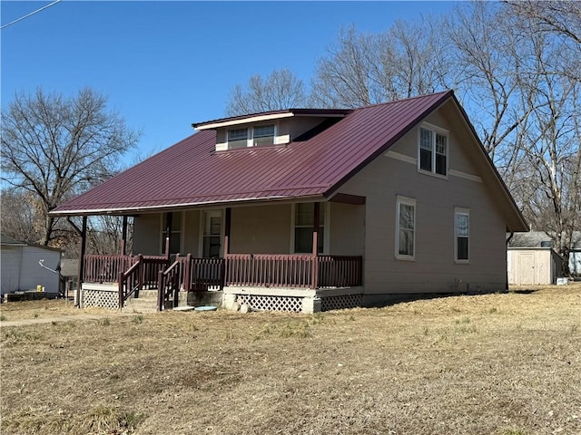 view of front of property featuring metal roof, a shed, a porch, and an outbuilding