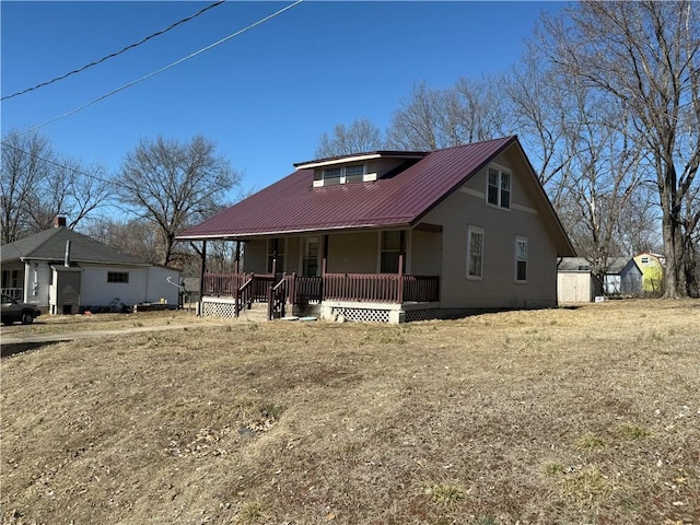 view of front of house featuring covered porch, metal roof, an outdoor structure, and a storage shed