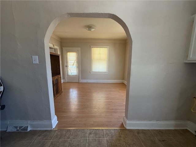 interior space featuring arched walkways, visible vents, baseboards, and tile patterned floors