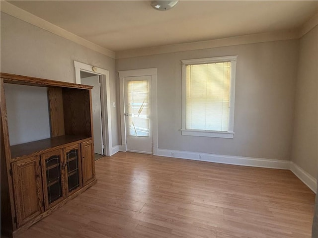 unfurnished living room with ornamental molding, light wood-style flooring, and baseboards