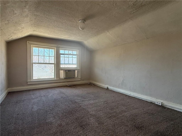 additional living space with a textured ceiling, lofted ceiling, cooling unit, carpet flooring, and baseboards