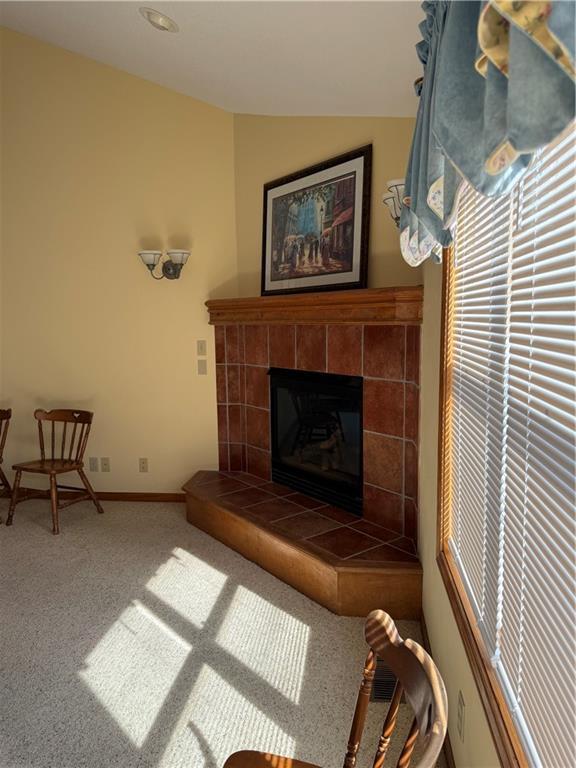 living room with carpet, baseboards, vaulted ceiling, and a tiled fireplace