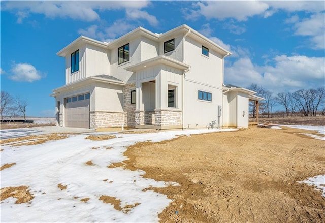 view of front of home with a garage, stone siding, and board and batten siding