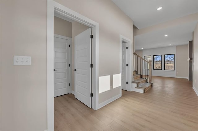 corridor with light wood-type flooring, stairs, baseboards, and recessed lighting