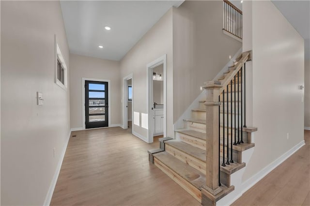 foyer with recessed lighting, baseboards, stairway, and light wood finished floors