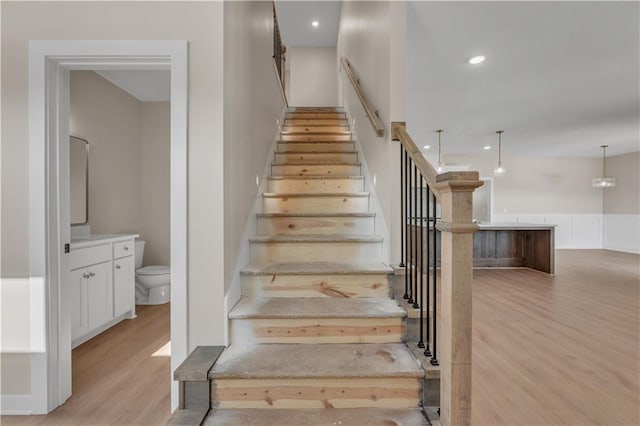 stairway with wood finished floors and recessed lighting