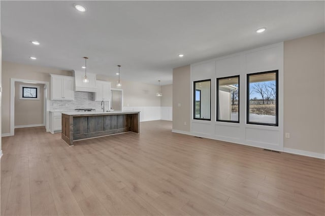 kitchen with light wood finished floors, light countertops, visible vents, decorative backsplash, and white cabinetry