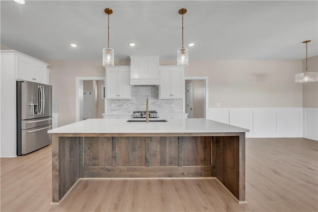 kitchen featuring light wood-type flooring, light countertops, a large island, and stainless steel fridge with ice dispenser