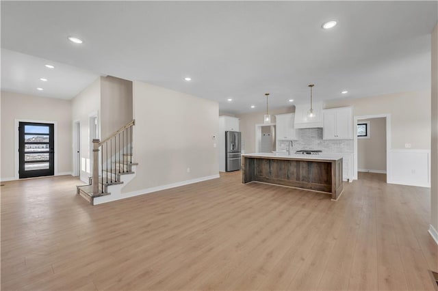 kitchen with white cabinetry, stainless steel fridge with ice dispenser, light countertops, light wood-type flooring, and decorative backsplash