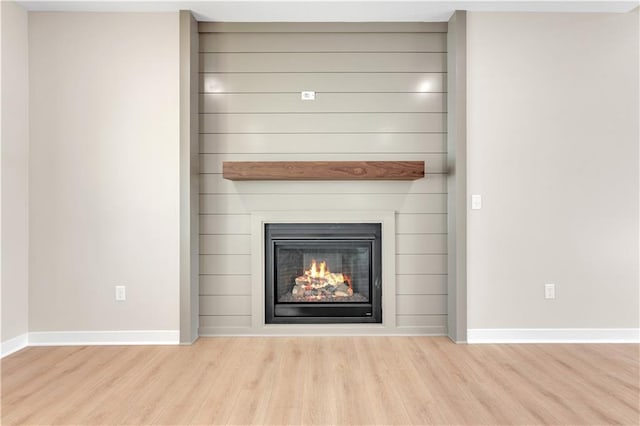 details featuring a large fireplace, baseboards, and wood finished floors