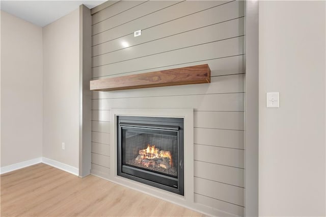 interior details with a large fireplace, baseboards, and wood finished floors