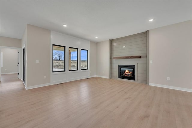 unfurnished living room with light wood finished floors, a fireplace, recessed lighting, and baseboards