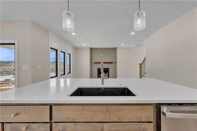 kitchen with dishwasher, open floor plan, light countertops, a fireplace, and a sink