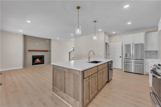 kitchen with stainless steel appliances, light wood-type flooring, a sink, and decorative backsplash