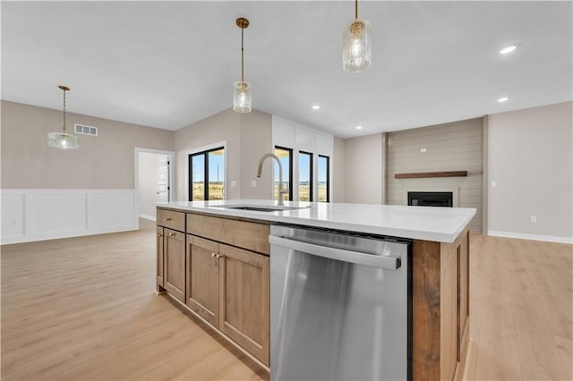 kitchen featuring light wood finished floors, visible vents, stainless steel dishwasher, open floor plan, and a sink