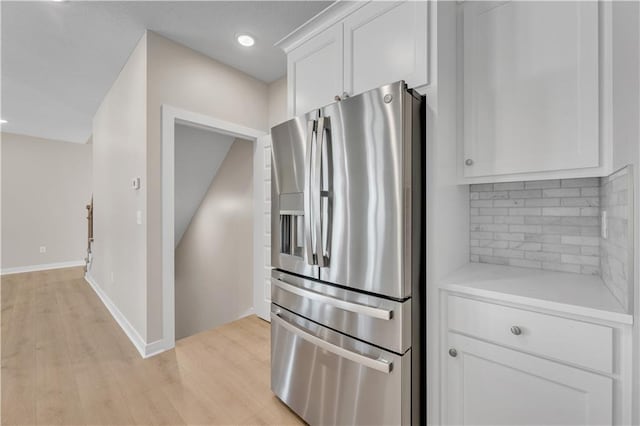 kitchen featuring light countertops, light wood-style floors, stainless steel refrigerator with ice dispenser, and white cabinets