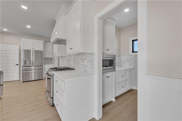 kitchen featuring tasteful backsplash, appliances with stainless steel finishes, light countertops, light wood-style floors, and white cabinetry