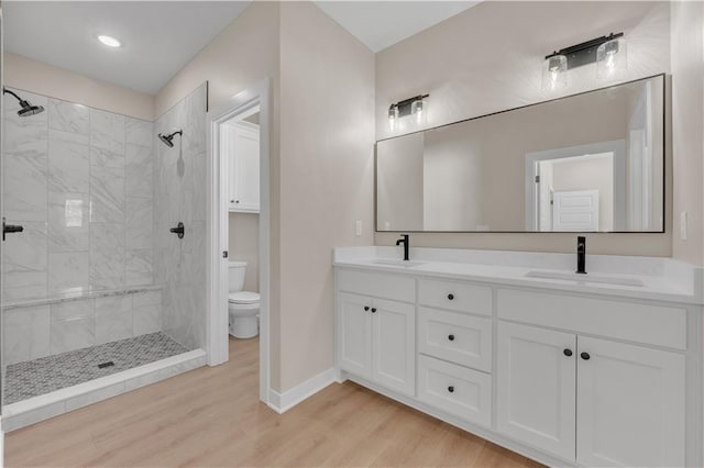 full bathroom featuring a sink, a tile shower, and wood finished floors