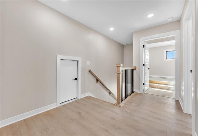 hall featuring recessed lighting, light wood-style flooring, baseboards, and an upstairs landing