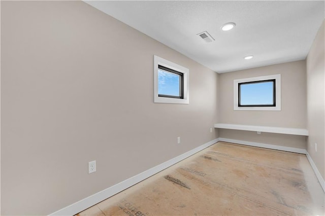 spare room featuring a healthy amount of sunlight, recessed lighting, visible vents, and baseboards