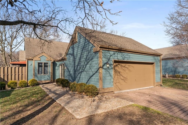 view of front of property featuring a garage, fence, decorative driveway, and roof with shingles