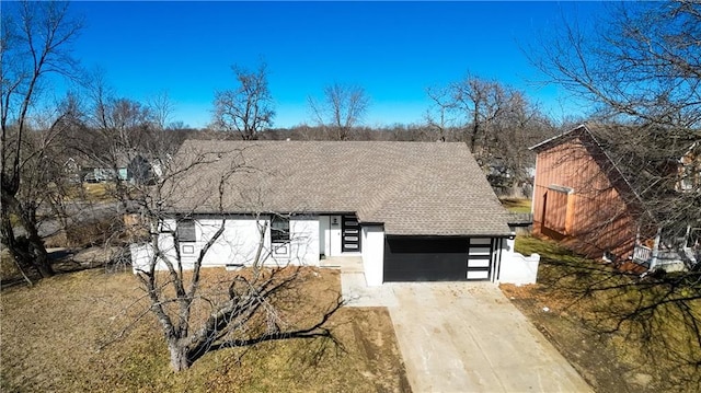 view of front of property with a shingled roof and concrete driveway