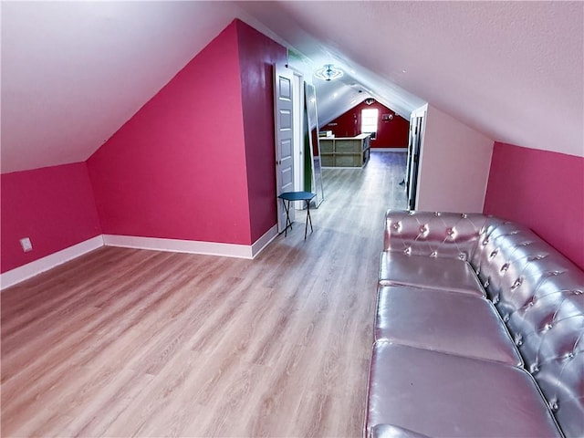 additional living space with lofted ceiling, a textured ceiling, baseboards, and wood finished floors