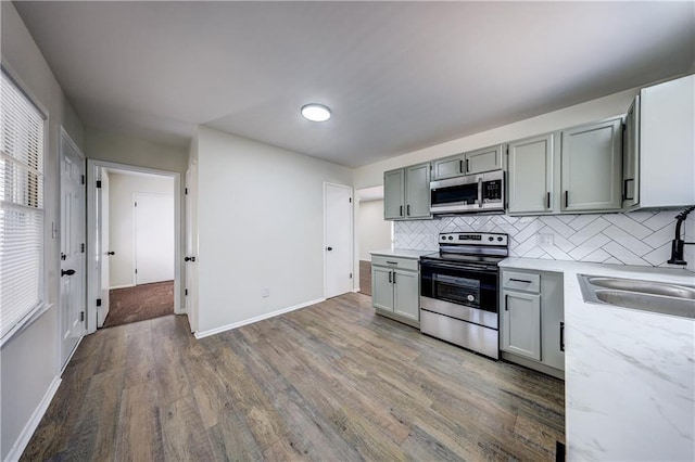 kitchen featuring decorative backsplash, wood finished floors, appliances with stainless steel finishes, and gray cabinetry