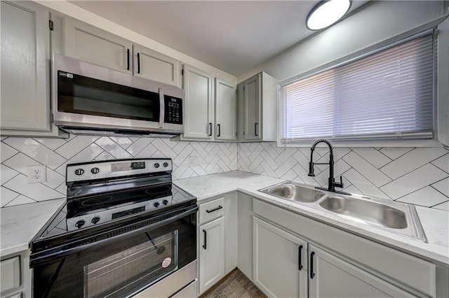 kitchen featuring electric range, backsplash, stainless steel microwave, and a sink